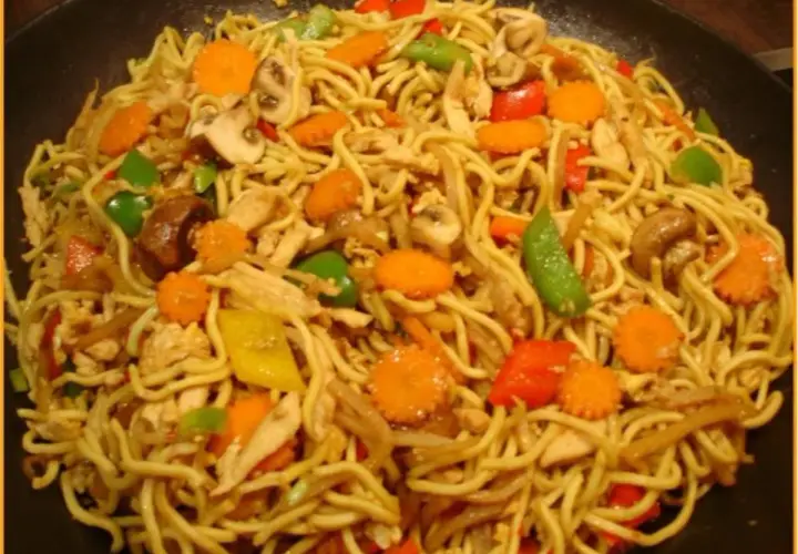 Ein Teller mit leckeren Mi Nudeln, garniert mit Hühnchen, Karotten, Pilzen und Paprika.