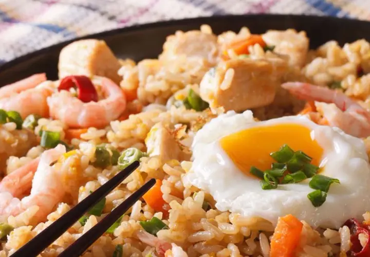 Nasi Goreng mit Garnelen, Hühnchen und einem Spiegelei, garniert mit Frühlingszwiebeln. Ein köstliches Gericht!