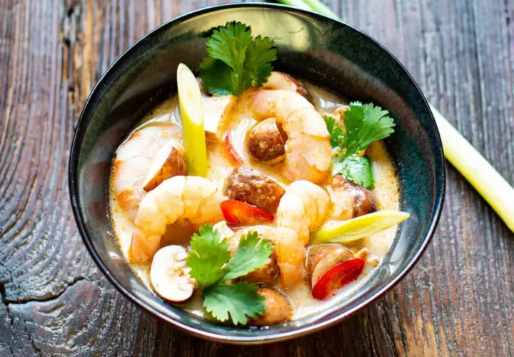 Eine Schüssel mit cremigem Tom Yam Gung, garniert mit Garnelen, Pilzen und Koriander.