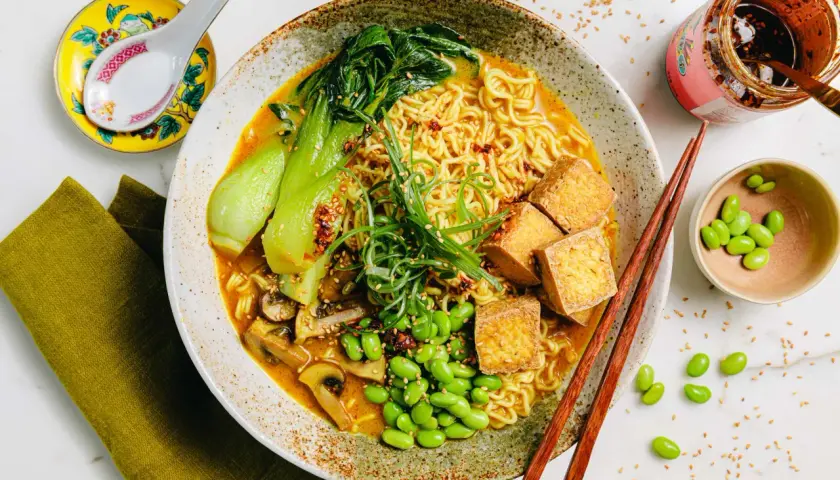 Schüssel mit Ramen-Nudeln, Bok Choy, Pilzen, Edamame und Tofuwürfeln. Die Vielfalt der **ramen toppings** macht dieses Gericht unwiderstehlich.