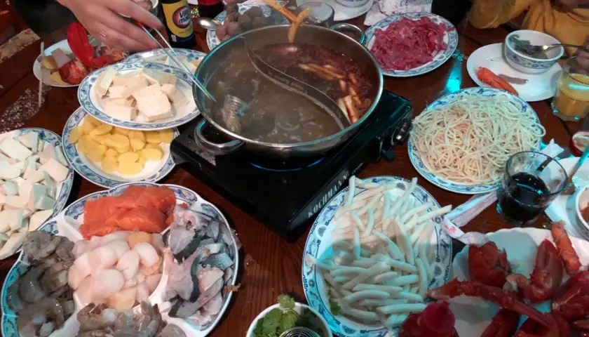 Ein Tisch voller Köstlichkeiten: Was ist Hot Pot? Hier werden frische Zutaten wie Garnelen, Lachs, Tofu und Nudeln in einer dampfenden Brühe gegart.