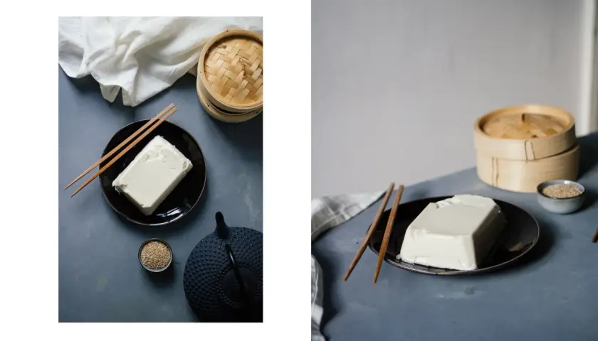 Ein Block Seidentofu auf einem Teller, daneben Stäbchen, eine Teekanne und Sesam. Was ist Seidentofu? Zart und cremig, ideal für asiatische Gerichte.