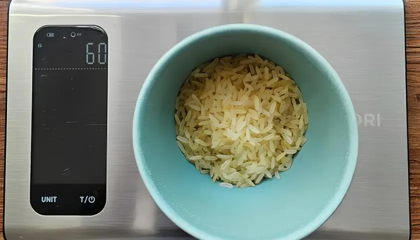 Eine Waage zeigt 60g Reis an. So behältst du die Reis Kalorien im Blick.