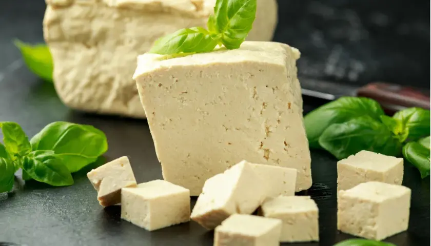 Frisch geschnittener Tofu, einige Würfel und ein ganzer Block, garniert mit Basilikum. Dieser ist tofu fermentiert und bereit für die Zubereitung.