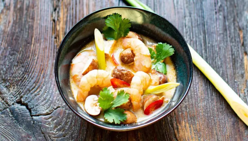 Eine Schüssel mit cremigem Tom Kha Gung, garniert mit Garnelen, Pilzen und Koriander.