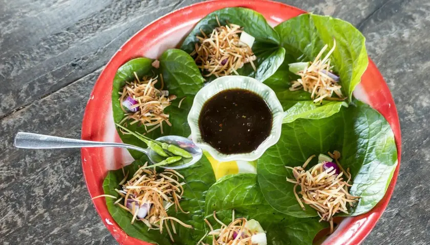 Miang Kham: grüne Blätter gefüllt mit knusprigen Nüssen, Zwiebeln und Limette, serviert mit Dip und Chilis.