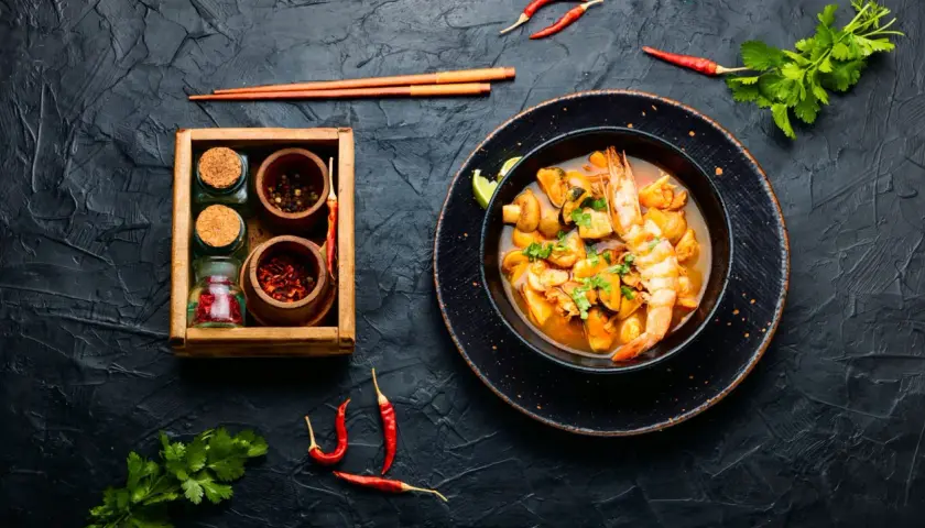 Würziges Meeresfrüchte-Curry mit Garnelen und Muscheln, daneben Gewürze. Was ist Fischsauce? Sie verleiht diesem Gericht Tiefe.