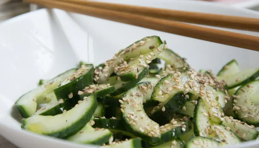 Frischer, knackiger koreanischer Gurkensalat mit Sesam bestreut, bereit zum Genießen mit Stäbchen.