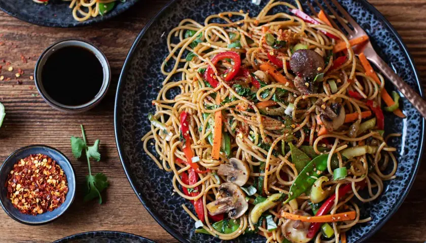 Ein köstliches asia nudeln gericht mit viel Gemüse und Pilzen, garniert mit Chiliflocken.