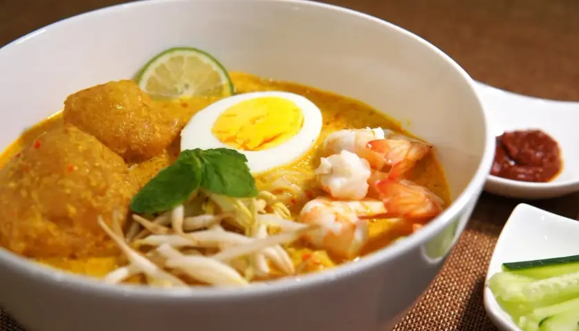 Schüssel mit cremigem Laksa-Rezept, Garnelen, Ei, frischen Sprossen und Limette.