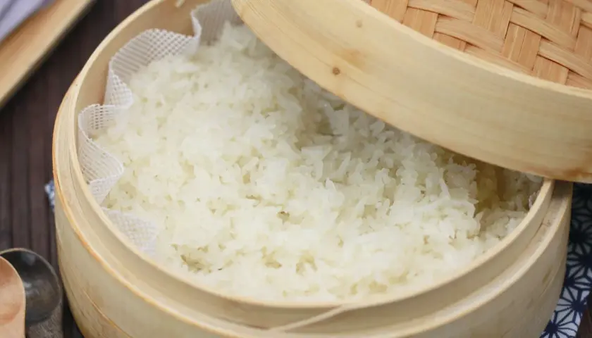 Frisch gedämpfter Klebreis kochen in einem Bambuskorb. Perfekt für asiatische Gerichte.