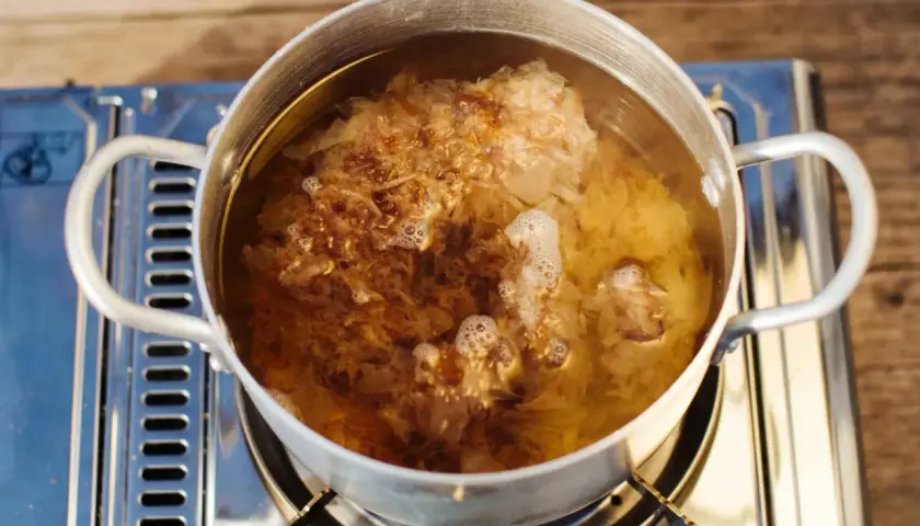 Ein Topf mit kochendem Wasser, in dem sich Flocken von Dashi no moto befinden, die ihren Umami-Geschmack freisetzen.