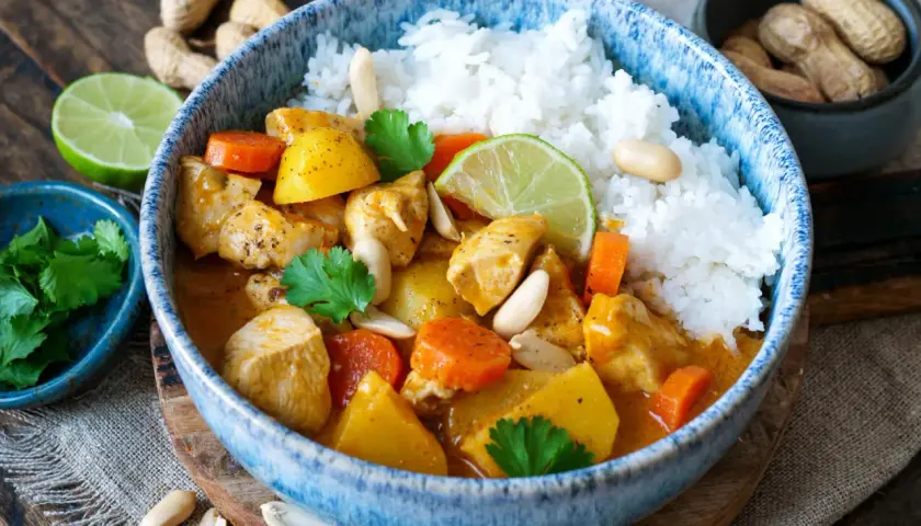 Hähnchen-Massaman-Curry mit Reis, Karotten, Kartoffeln, Erdnüssen und Koriander.