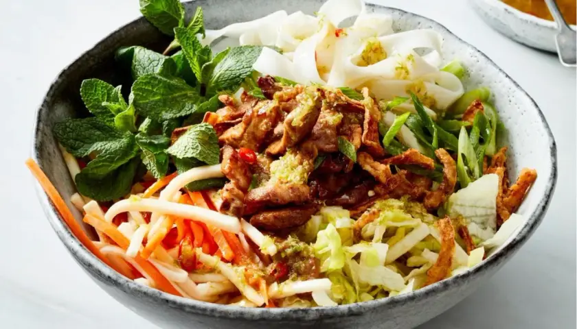 Herzhafte Reisnudel bowl mit zartem Fleisch, knackigem Gemüse und frischer Minze.