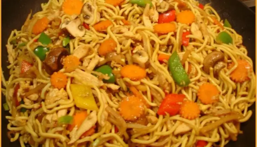 Ein Teller mit leckeren Mi Nudeln, garniert mit Hühnchen, Karotten, Pilzen und Paprika.