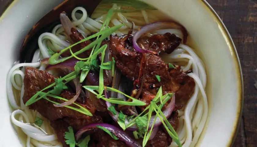 Herzhaftes Pho Kho mit zarten Rindfleischstreifen, Reisnudeln, roten Zwiebeln und Frühlingszwiebeln in einer aromatischen Brühe.