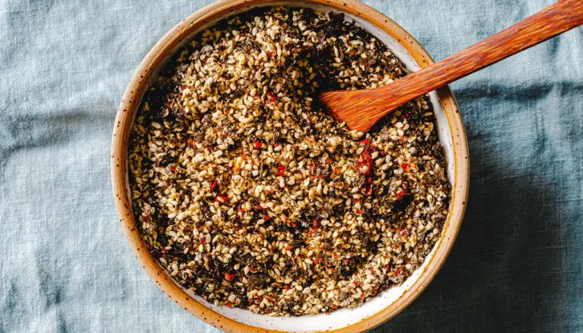 Schüssel mit selbstgemachtem Furikake, einer Mischung aus Sesam, Algen und Chili. Ein Holzspatel liegt darin.