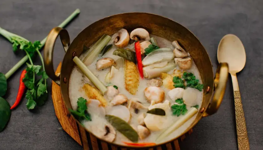Eine Schüssel mit cremigem Tom Kha mit Pilzen, Zitronengras und Chili. Die Tom Kha Sauce duftet aromatisch.