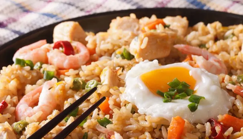 Nasi Goreng mit Garnelen, Hühnchen und einem Spiegelei, garniert mit Frühlingszwiebeln. Ein köstliches Gericht!