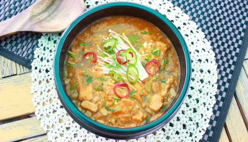 Herzhafter Eintopf mit Doenjang Sauce, Enoki-Pilzen und Chili-Scheiben, serviert in einer Schüssel.