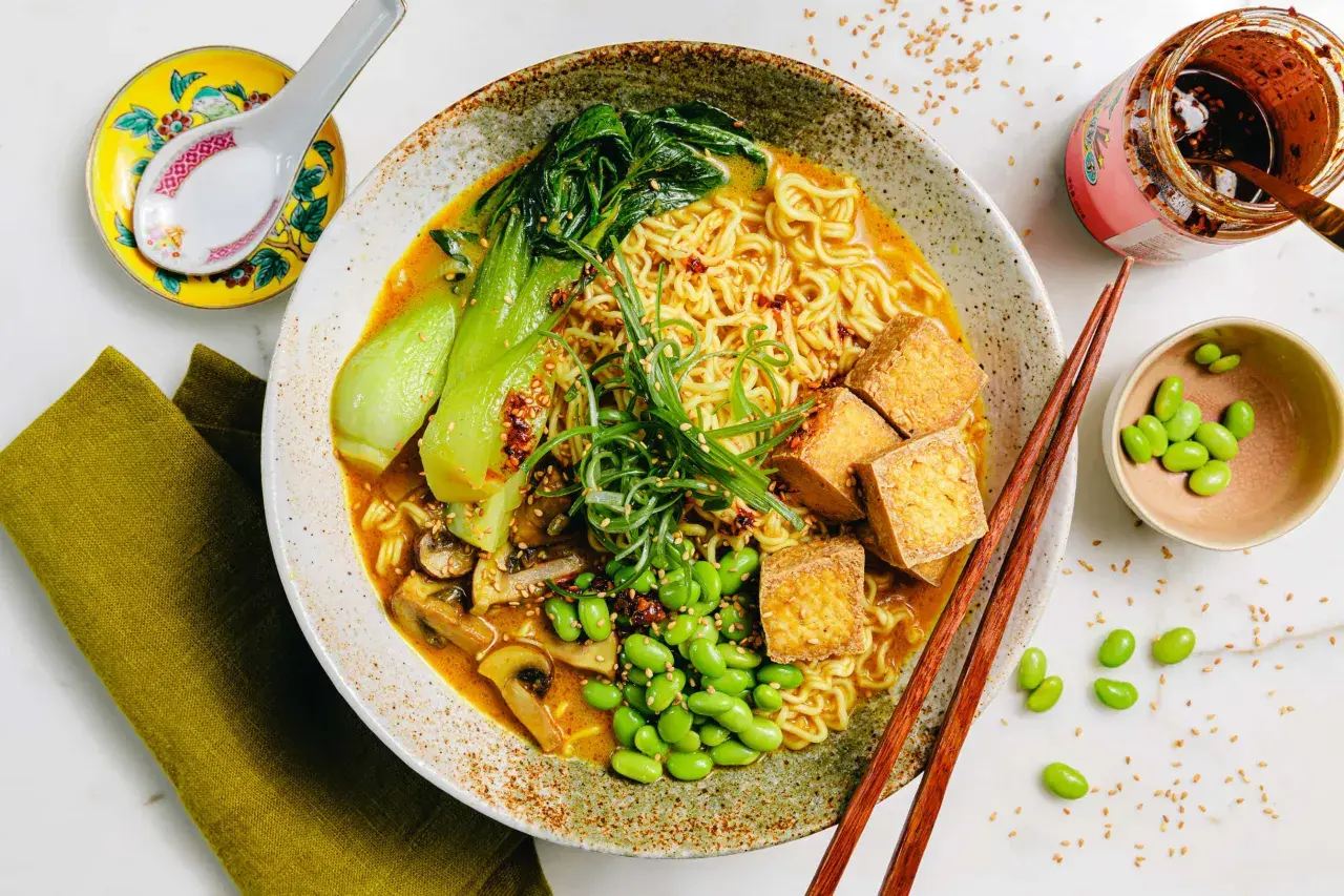 Schüssel mit Ramen-Nudeln, Bok Choy, Pilzen, Edamame und Tofuwürfeln. Die Vielfalt der **ramen toppings** macht dieses Gericht unwiderstehlich.