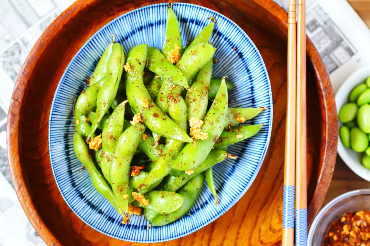 Schüssel mit gewürzten Edamame-Schoten, eine gesunde Quelle für Edamame Proteine, bereit zum Genuss mit Stäbchen.