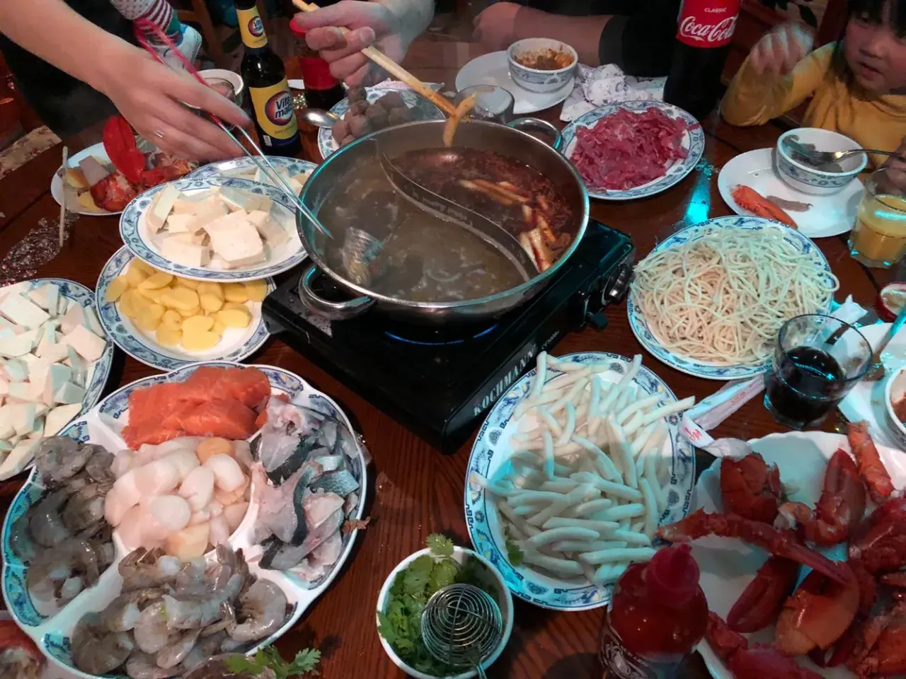 Ein Tisch voller Köstlichkeiten: Was ist Hot Pot? Hier werden frische Zutaten wie Garnelen, Lachs, Tofu und Nudeln in einer dampfenden Brühe gegart.
