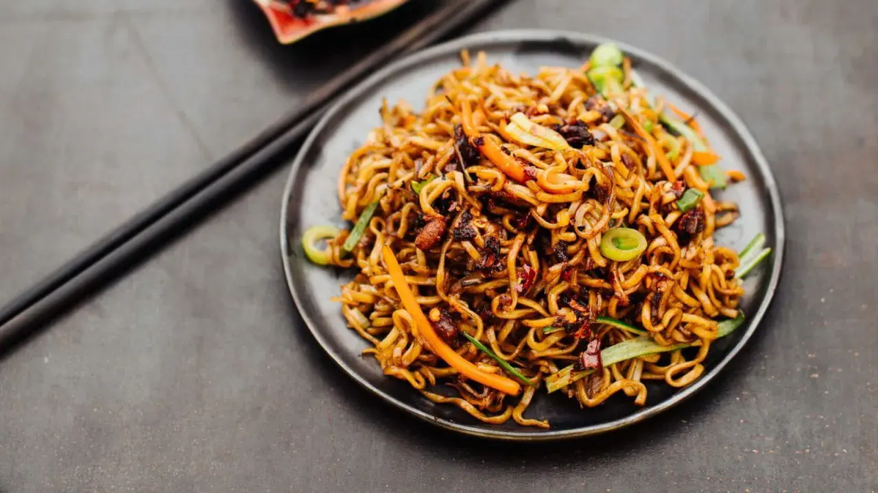 Ein Teller mit leckerem Chow Mein, garniert mit Frühlingszwiebeln und Karotten. Perfekt für ein schnelles, herzhaftes Essen.