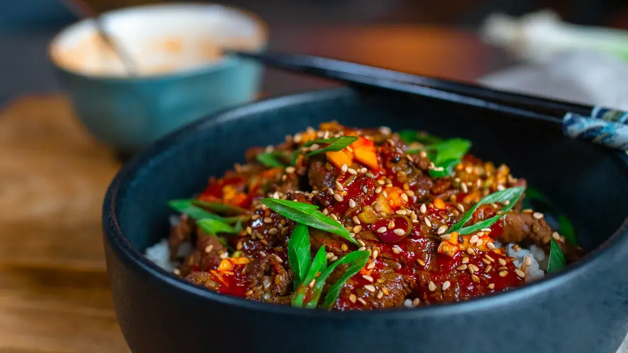 Schüssel mit Reis und würzigem Rindfleisch, garniert mit Frühlingszwiebeln und Sesam. Eine köstliche bulgogi sauce alternative.