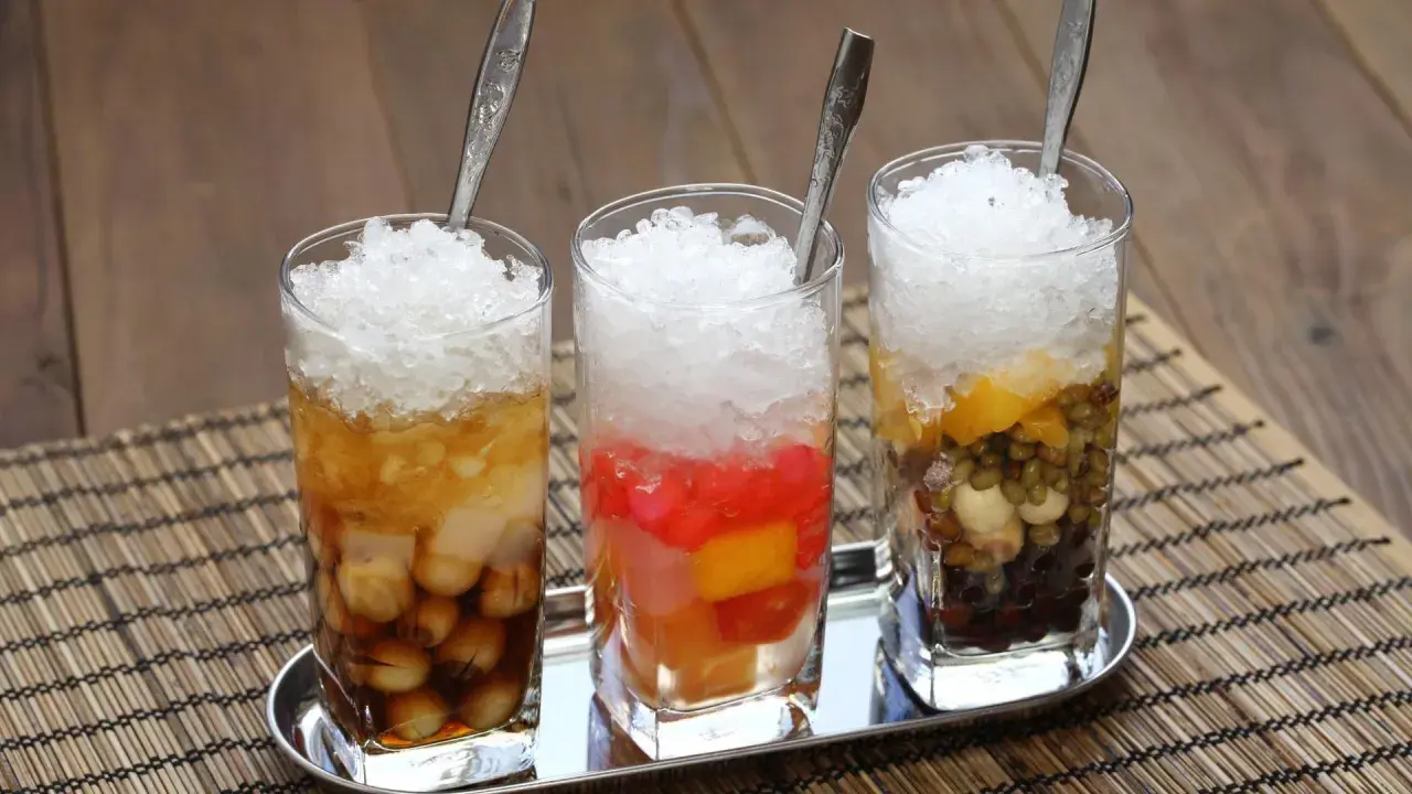 Drei Gläser mit zerstoßenem Eis und bunten Zutaten, ein erfrischendes che vietnam.