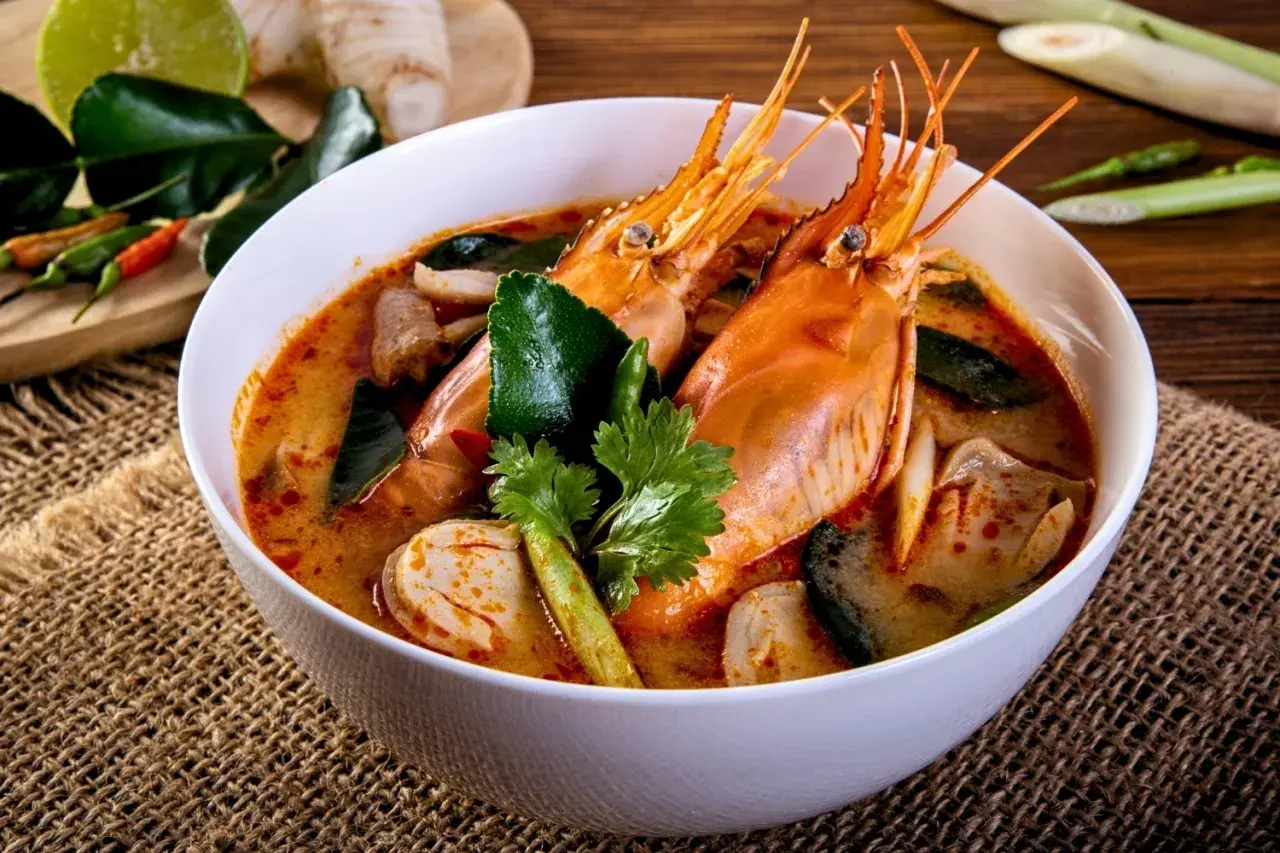 Eine Schüssel Tom Yum Suppe mit Garnelen, Pilzen und Kaffirlimettenblättern, garniert mit Koriander.