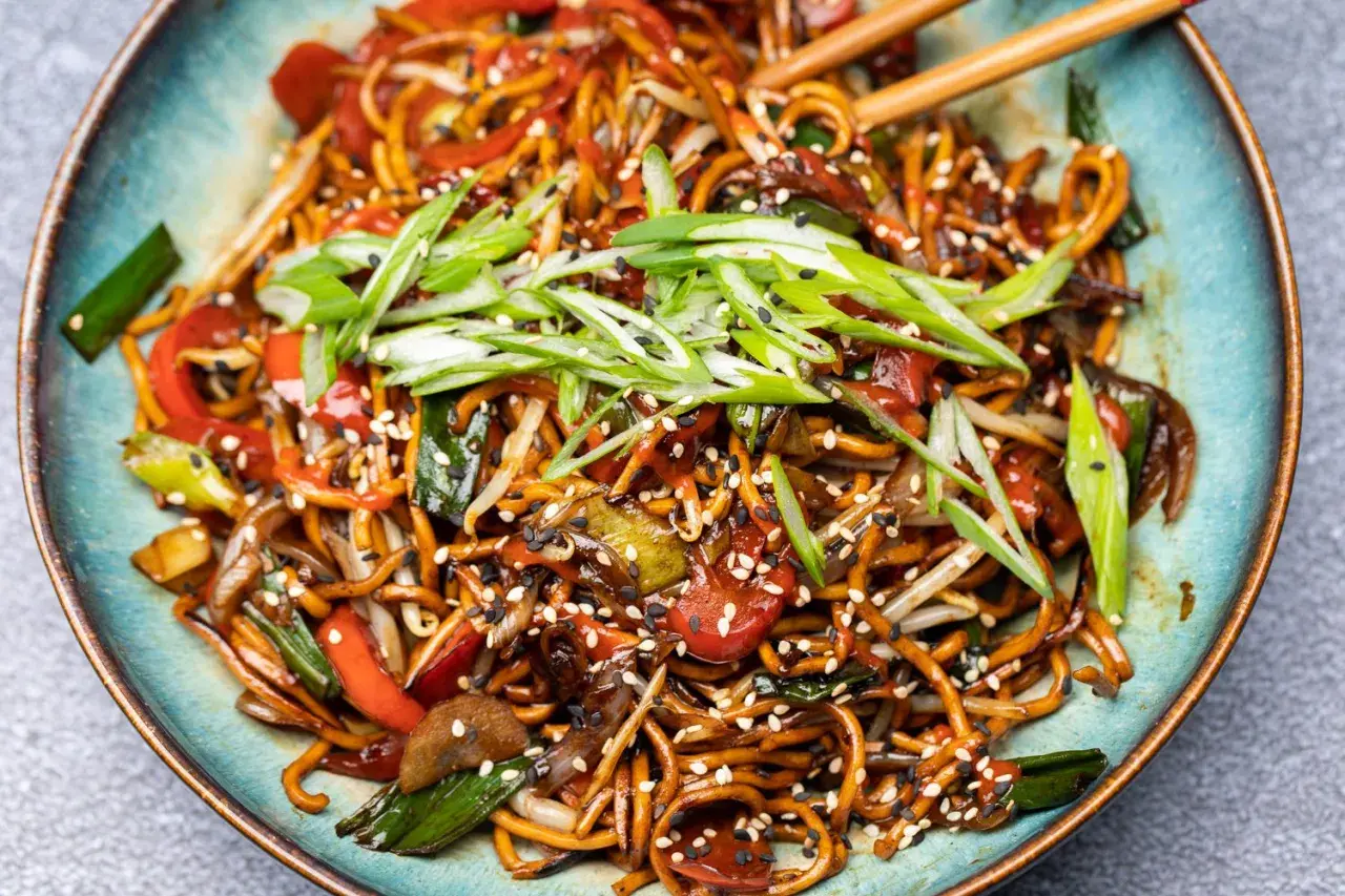 Chao mian Nudeln mit Gemüse, garniert mit Frühlingszwiebeln und Sesam.