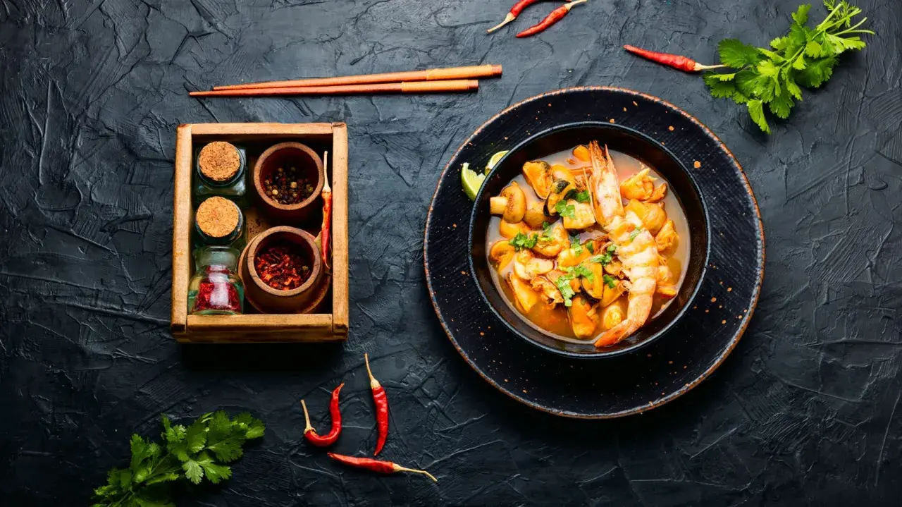 Würziges Meeresfrüchte-Curry mit Garnelen und Muscheln, daneben Gewürze. Was ist Fischsauce? Sie verleiht diesem Gericht Tiefe.