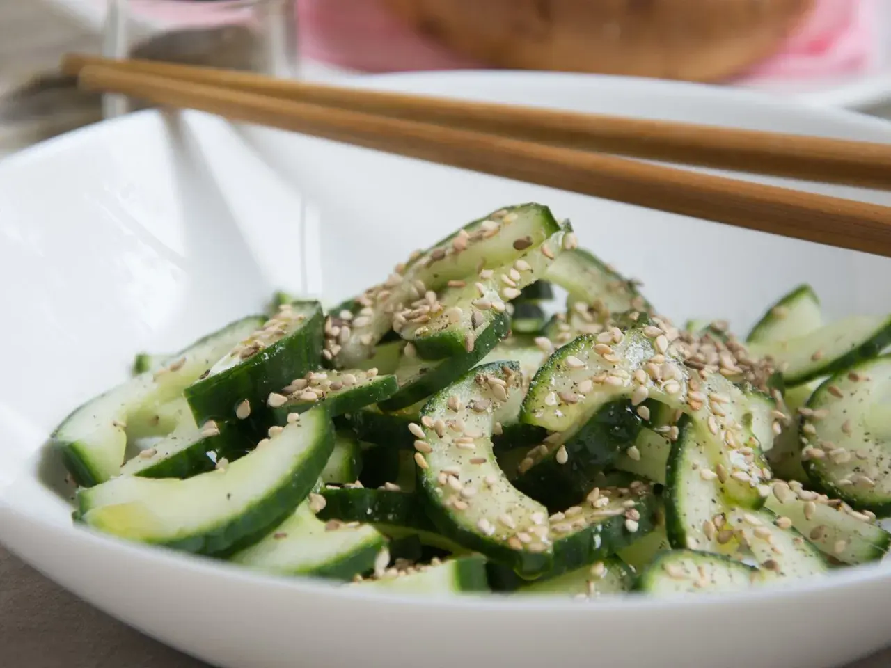 Frischer, knackiger koreanischer Gurkensalat mit Sesam bestreut, bereit zum Genießen mit Stäbchen.