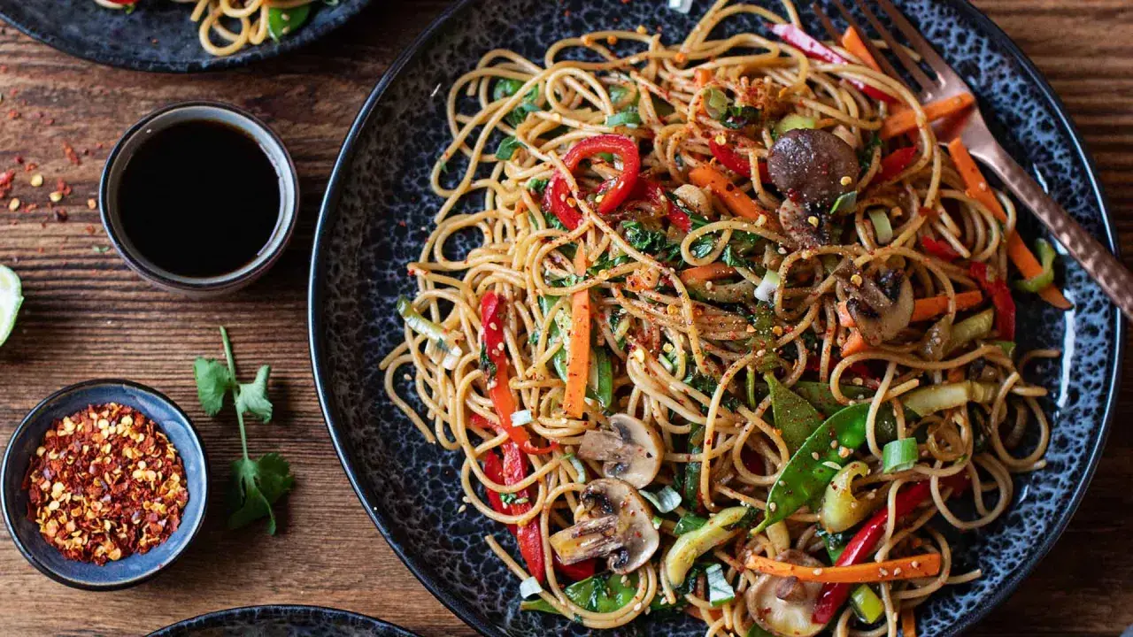 Ein köstliches asia nudeln gericht mit viel Gemüse und Pilzen, garniert mit Chiliflocken.