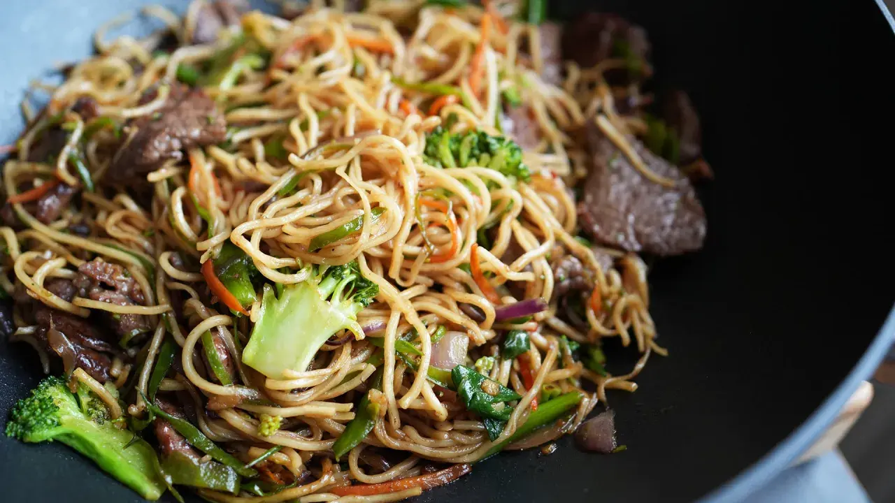 Leckere asiatische Nudeln kochen mit Rindfleisch, Brokkoli, Karotten und Paprika in einem Wok.