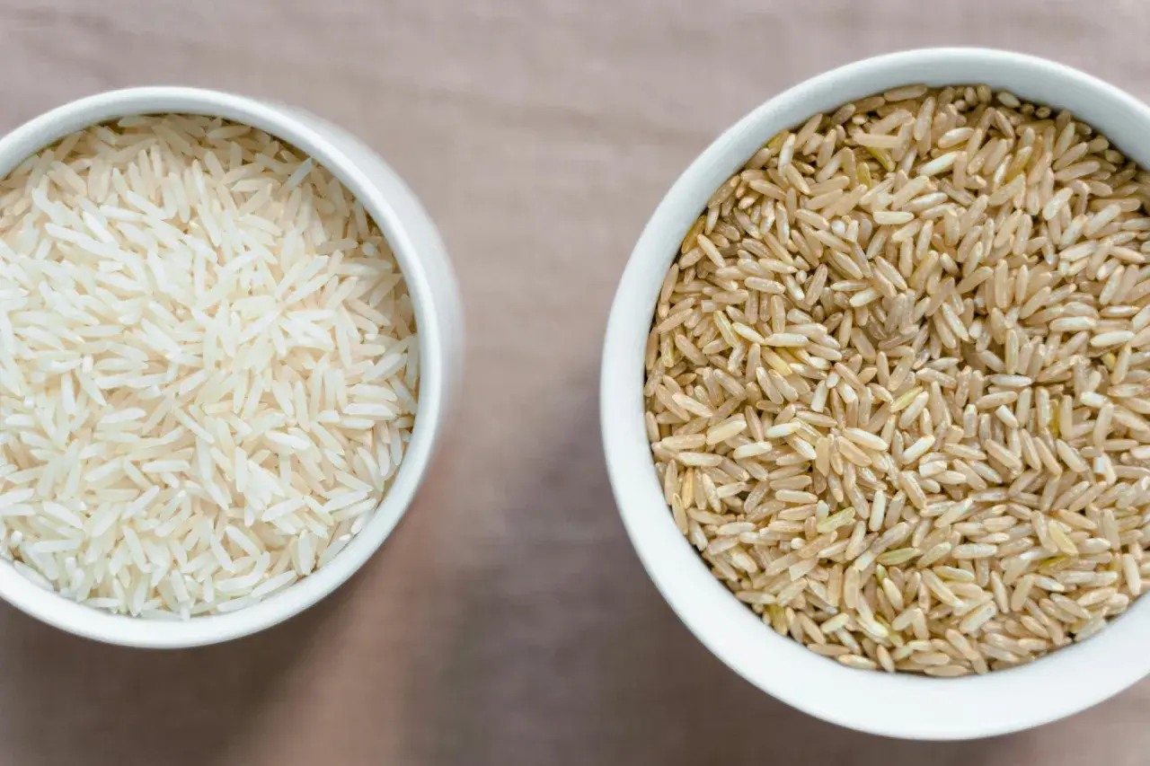 Zwei Schalen mit Reis: links weißer Basmati oder Jasmin Reis, rechts brauner Reis.