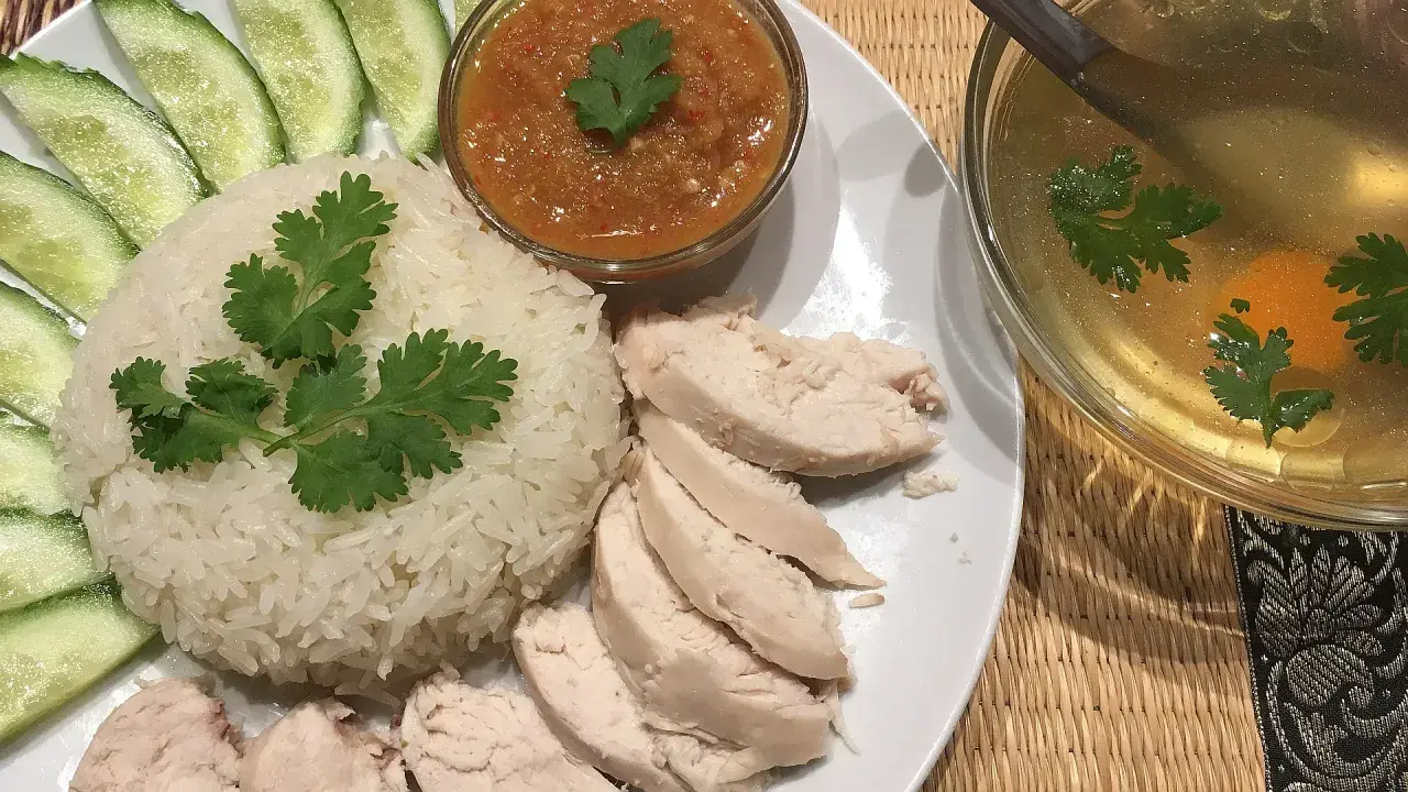 Khao man gai: Reis, Hähnchen, Gurkenscheiben, scharfe Sauce und eine klare Brühe mit Ei und Koriander.