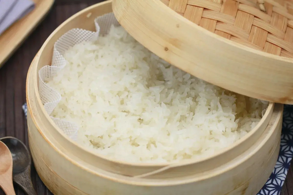 Frisch gedämpfter Klebreis kochen in einem Bambuskorb. Perfekt für asiatische Gerichte.