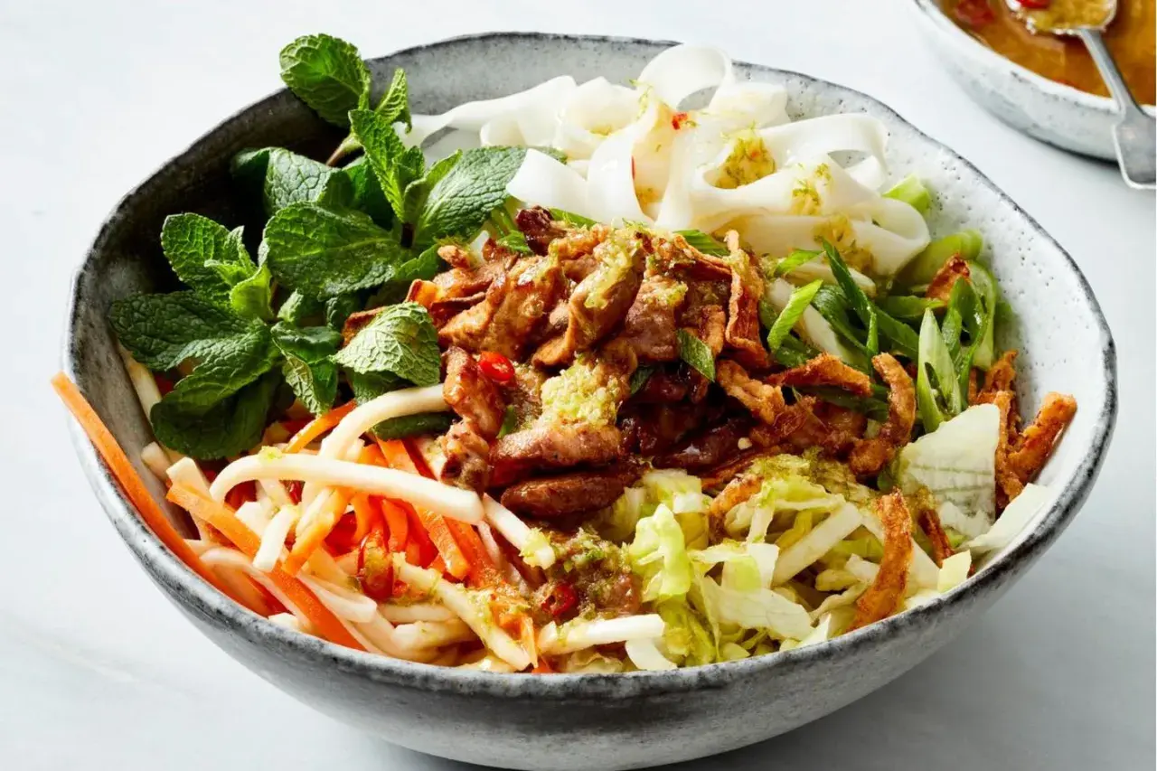 Herzhafte Reisnudel bowl mit zartem Fleisch, knackigem Gemüse und frischer Minze.