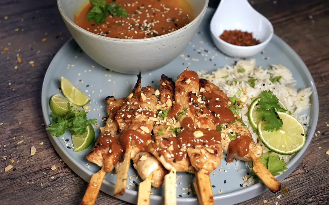 Saftige sate spiesse mit Erdnusssauce, Reis, Limettenspalten und Koriander. Ein Fest für die Sinne!