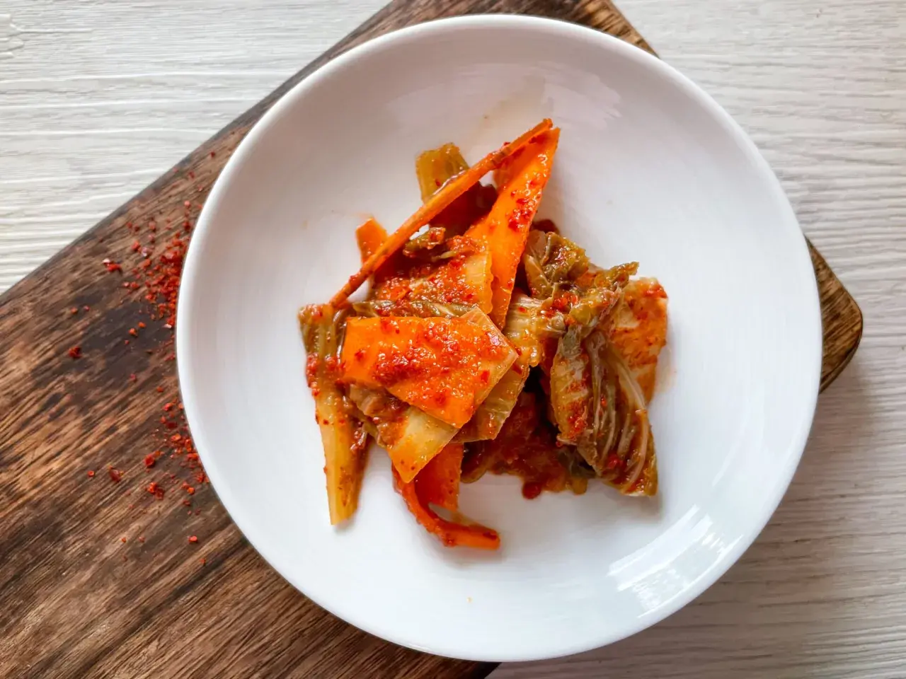 Frisch zubereitetes Kimchi, ein köstliches Rezept, serviert auf einem weißen Teller mit karamellisierten Karottenstreifen und Chinakohl.