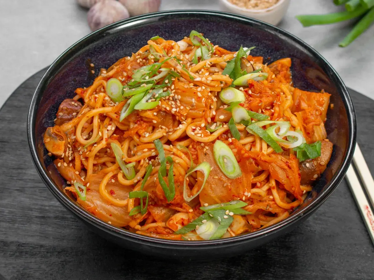 Eine Schüssel mit würzigem Kimchi Ramen, garniert mit Frühlingszwiebeln und Sesam.