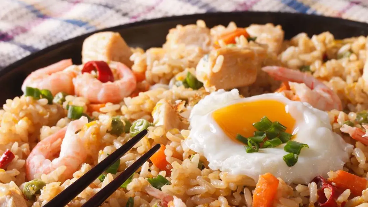 Nasi Goreng mit Garnelen, Hühnchen und einem Spiegelei, garniert mit Frühlingszwiebeln. Ein köstliches Gericht!