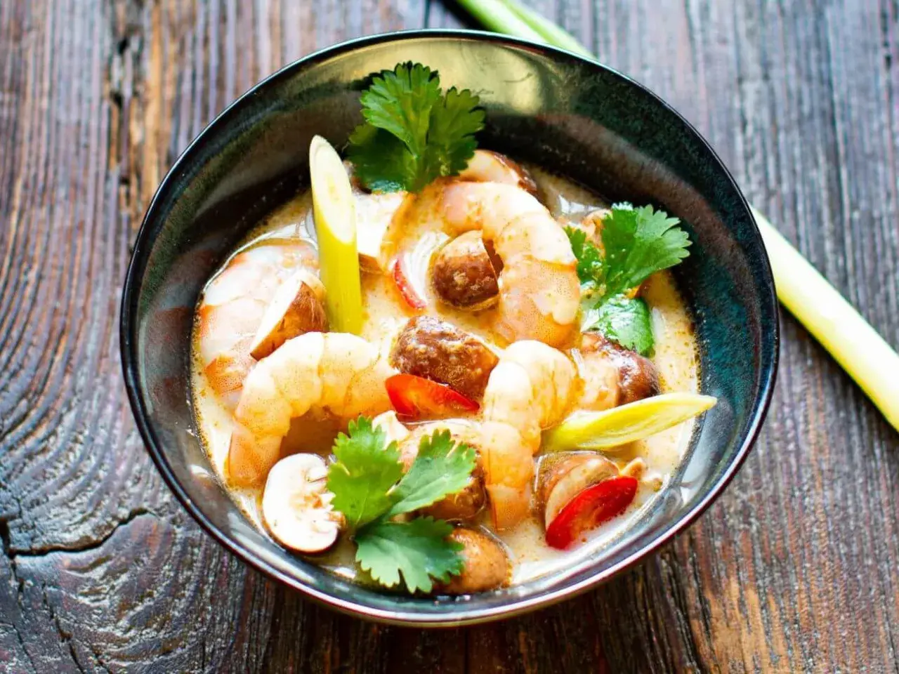 Eine Schüssel mit cremigem Tom Yam Gung, garniert mit Garnelen, Pilzen und Koriander.