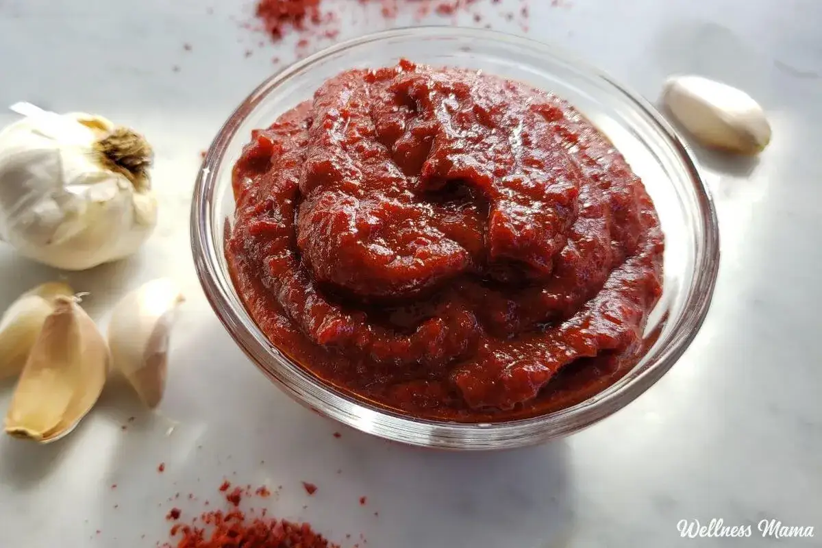 Sch&uuml;ssel mit Gochujang Paste, dane daneben Knoblauch und Chilipulver. Die Zutaten f&uuml;r Gochujang sind bereit.