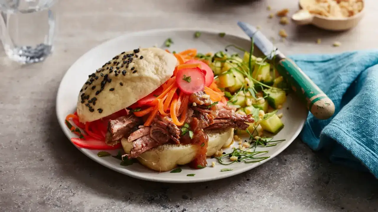 Ein saftiger bao burger mit zartem Fleisch, Karottenstreifen und Radieschen. Dazu ein frischer Gurkensalat.