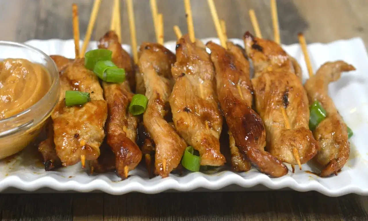 Saftige sate spieße mit Erdnusssauce und Frühlingszwiebeln garniert.