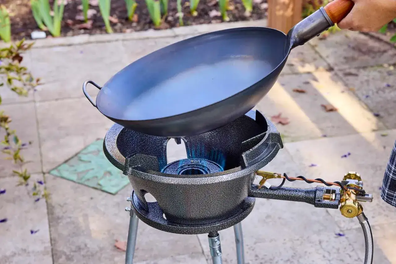 Ein Wok steht über einer Gasflamme, bereit für die Zubereitung von Reis.