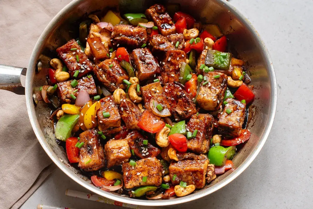 Gebratener Tofu mit Paprika, Zwiebeln und Cashewkernen in einer Pfanne. Ein köstliches Gericht, das zeigt, was ist Tofu.